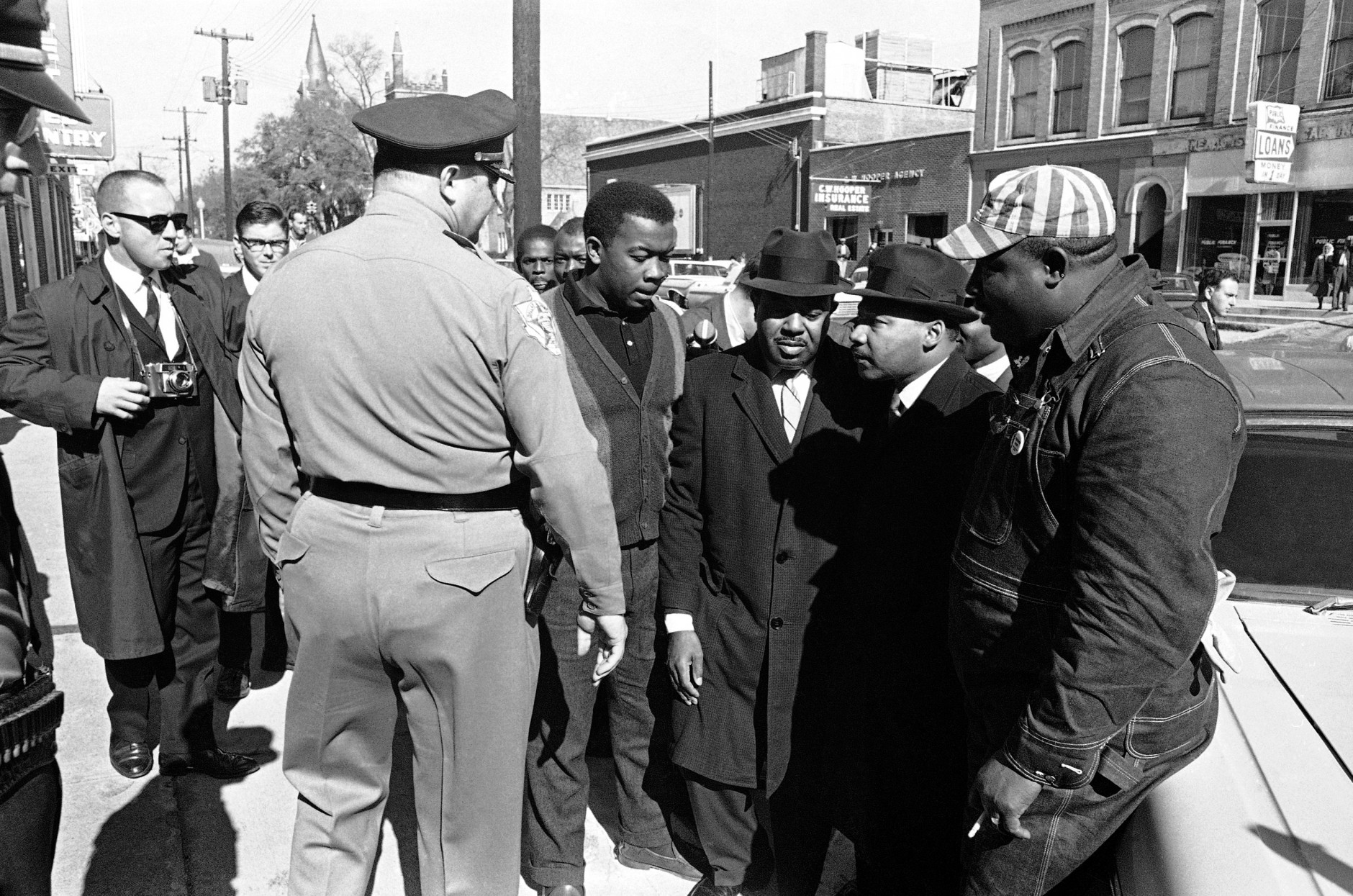 Dr. Martin Luther King Jr., right, and Dallas County Sheriff Jim Clark glare at each other in Selma, Alabama on Jan. 26, 1965 as the sheriff orders King to stand off of sidewalk as he watches African Americans stand in line to register to vote. The sheriff kept everyone from blocking the sidewalk. Several incidents broke out and several were arrested. (AP Photo/Horace Cort)