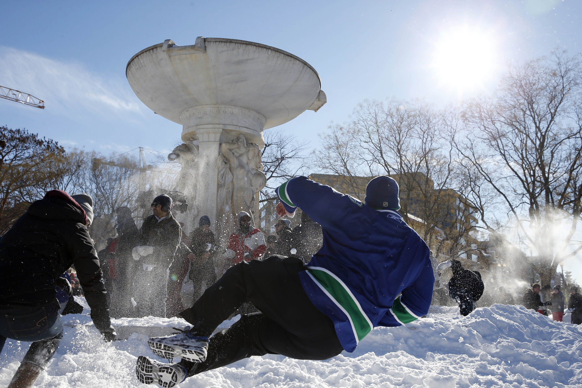 A man does a flying move to throw his snowball during an organized snowball fight at Dupont Circle Sunday, Jan. 24, 2016 in Washington. (AP Photo/Alex Brandon)