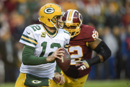 Aaron Rodgers scrambles with the ball under pressure from Washington Redskins defensive end Chris Baker (92) during the first half of an NFL wild card playoff football game in Landover, Md., Sunday, Jan. 10, 2016. (AP Photo/Nick Wass)