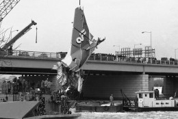 The tail section of the Air Florida jetliner that crashed in the Potomac River in Washington on Wednesday is hoisted by a crane onto a floating barge after being removed, Monday, Jan. 19, 1982 from the water. A span of the 14th Street bridge which the plane did not hit is shown in background. (AP Photo)