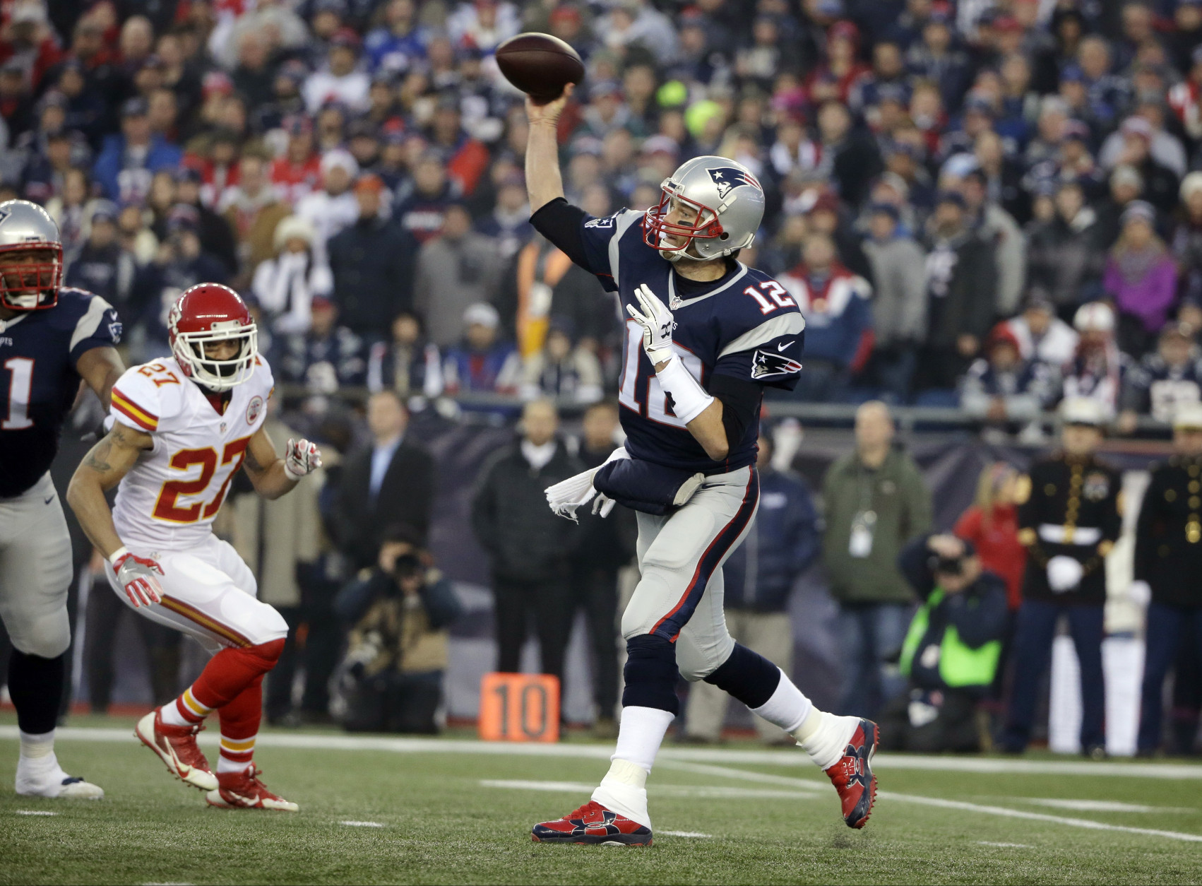 El quarterback Tom Brady (12) de los Patriots de Nueva Inglaterra lanza un pase ante el asedio de 
Tyvon Branch (27) de los Chiefs de Kansas City en los playoffs de la NFL el sábado 16 de enero de 2016. (AP Foto/Steven Senne)