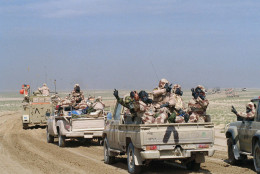 Kuwaiti troops wearing gas masks and protective suits as they roll through southern Kuwait in an armed motor convoy, Sunday, Feb. 24, 1991, the first full day of ground conflict in Operation Desert Storm. Allied troops encountered resistance in some areas, but no use of gas weapons was reported. Inverted "V" painted on vehicles is the allied recognition symbol. (AP Photo/Laurent Rebours)