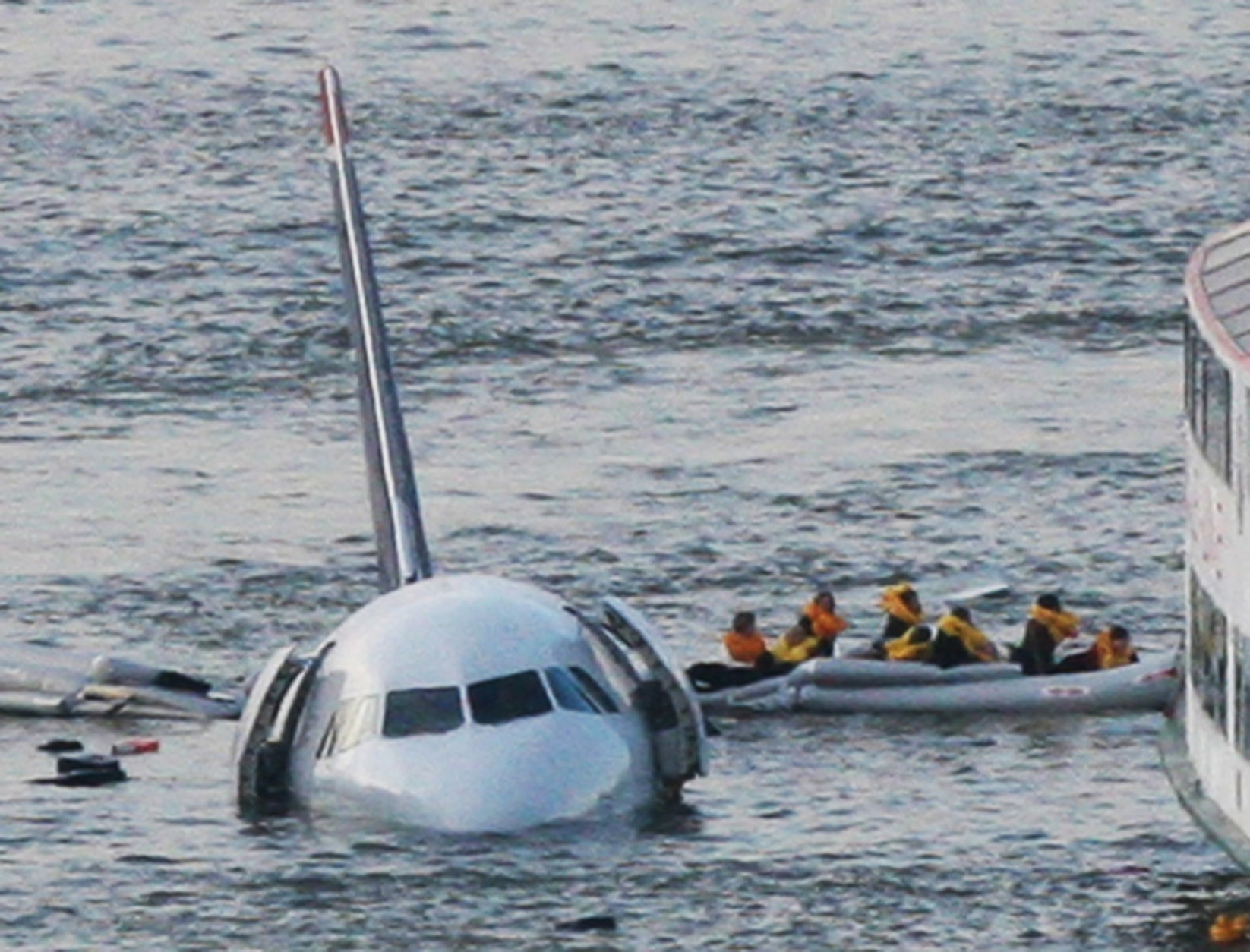 FILE - In this Jan. 15, 2009 file photo, passengers in an inflatable raft move away from US Airways Flight 1549 that went down in the Hudson River in New York. The jet ditched in the Hudson River after both engines failed when they ingested birds shortly after takeoff. All 155 people on board were safe; Captain Chesley Sullenberger and other crew members were hailed as heroes. (AP Photo/Bebeto Matthews, File)
