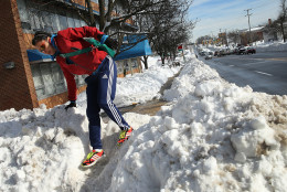 ARLINGTON, VA - JANUARY 25:  Nina Hernandez climbs over a large pile of snow plowed across the sidewalk as she makes her way to the grocery store January 25, 2016 in Arlington, Virginia. Winter Storm Jonas hit the East Coast over the weekend, breaking snowfall records, causing 29 storm-related deaths, leaving thousands of homes without power and serious flooding in coastal areas. (Photo by Win McNamee/Getty Images)