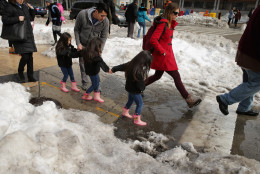 WASHINGTON, DC - JANUARY 26:  Adults and children traverse piles of snow and slush puddles in a busy shopping area in the Columbia Heights neighborhood following the weekend blizzard January 26, 2016 in Washington, DC. The east coast is still digging out from Winter Storm Jonas that hit the East Coast over the weekend, breaking snowfall records, causing 29 storm-related deaths, and serious flooding in coastal areas. (Photo by Chip Somodevilla/Getty Images)