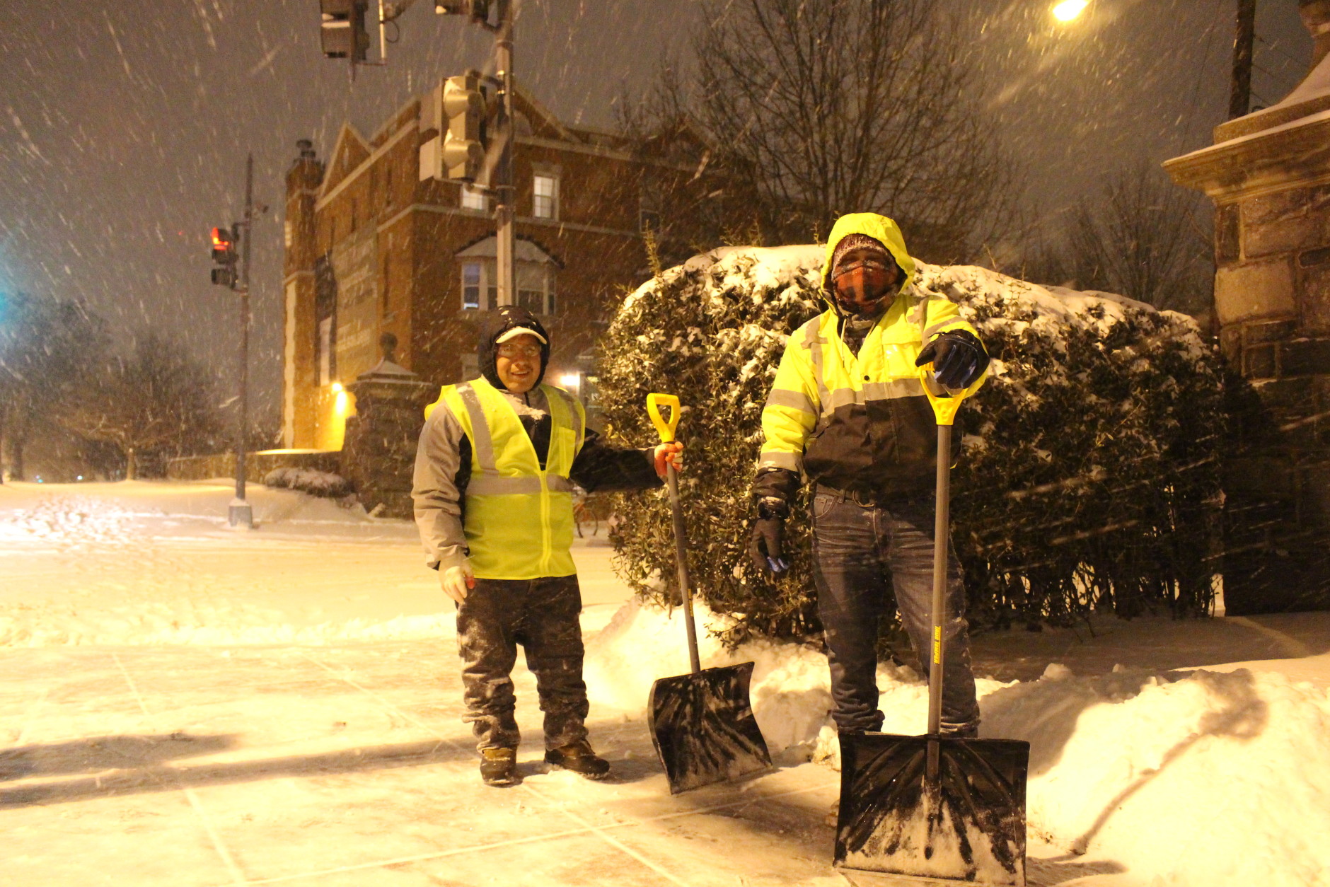 Two snow shovelers took a break while clearing sidewalks on Wisconsin Avenue on Friday night. (WTOP/Dana Gooley)