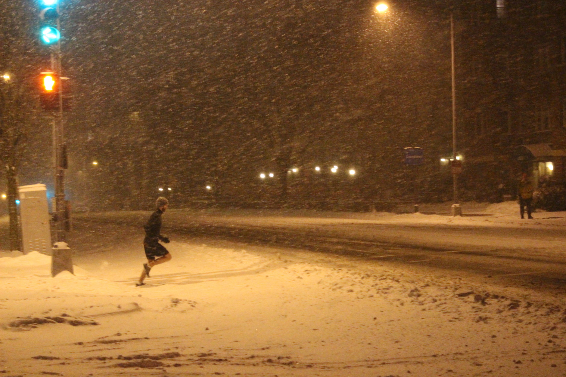 A dedicated runner crosses Wisconsin Avenue on Friday night. (WTOP/Dana Gooley)