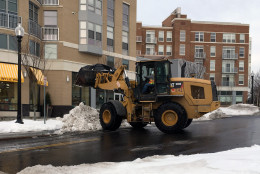 A front loaders dumps snow into a truck in McLean Gardens off Wisconsin Avenue in D.C. Thursday. (WTOP/Meera Pal)