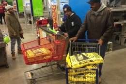 George Currie of Oxon Hill on left, doesn't need the 200 pounds of ice melt in his cart. "I can't say what other people would do. But this is in our [he and his wife’s] hearts to get enough so if someone doesn't have - it's enough for them too." 