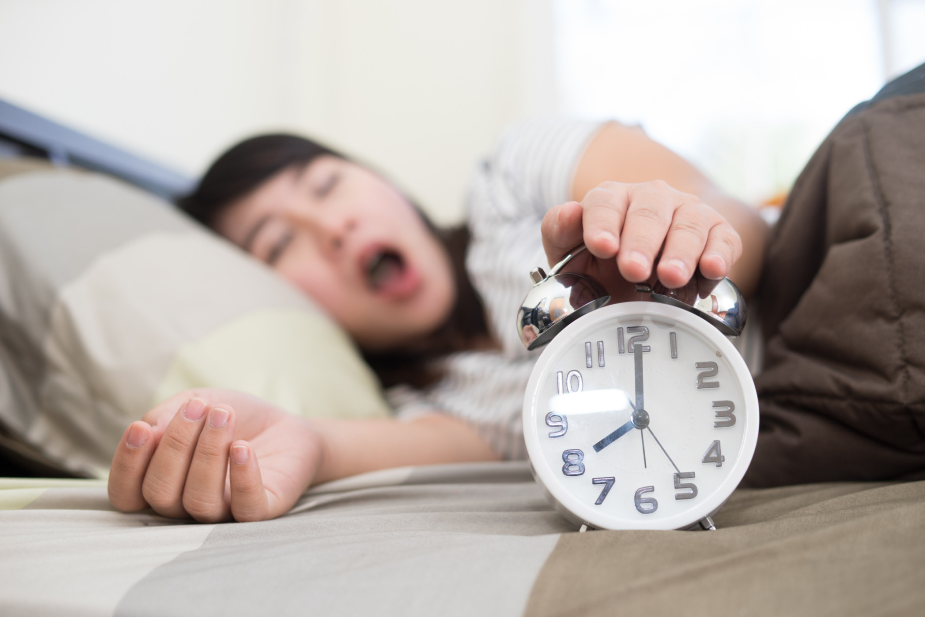 Yawning woman with alarm clock.