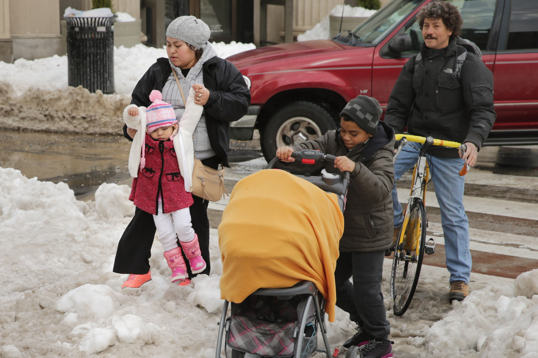 WASHINGTON, DC - JANUARY 26:  Adults and children traverse piles of snow and slush puddles in a busy shopping area in the Columbia Heights neighborhood following the weekend blizzard January 26, 2016 in Washington, DC. The east coast is still digging out from Winter Storm Jonas that hit the East Coast over the weekend, breaking snowfall records, causing 29 storm-related deaths, and serious flooding in coastal areas.  (Photo by Chip Somodevilla/Getty Images)