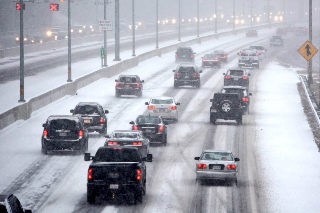 Traffic moves along a snow-covered Interstate 395 in Alexandria, Virginia, as of 3:20 p.m. Friday. As the fast-falling snow moved in, roads quickly became covered. (WTOP/Dave Dildine)