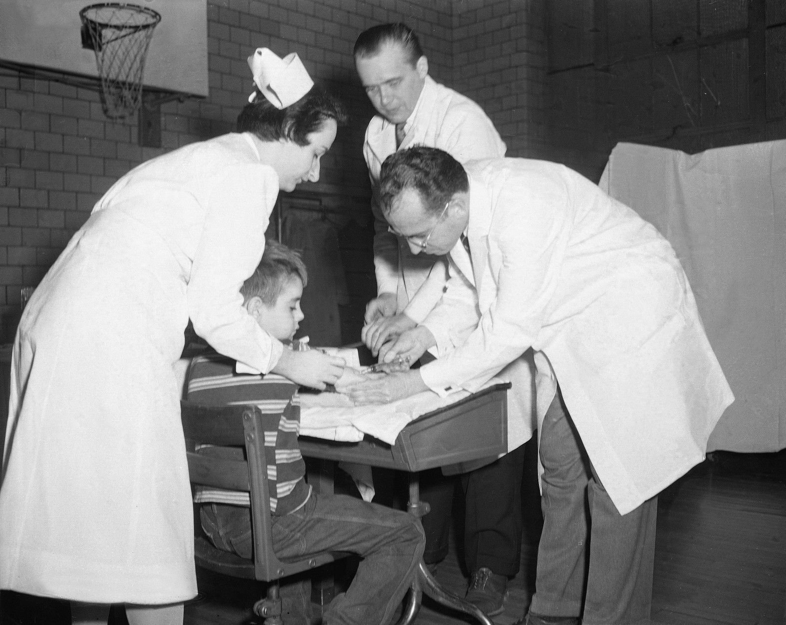 Dr. Jonas Salk, Pittsburgh scientist who discovered the Polio vaccine, administers an injection to an unidentified boy at Arsenal Elementary School in Pittsbrugh, Pa., Feb. 23, 1954.  (AP Photo)