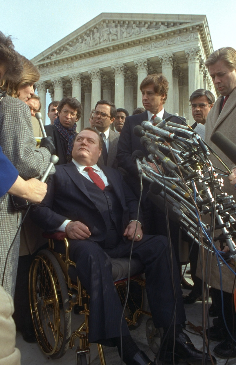 Wheelchair-bound Hustler publisher Larry Flynt is surrounded by reporters outside the U.S. Supreme Court building in Washington December 2, 1987.  In a lawsuit filed by the Rev. Jerry Falwell, the Supreme Court sided with Flynt, who claimed a First Amendment right to parody Falwell in his magazine. (AP Photo/Charles Tasnadi)
