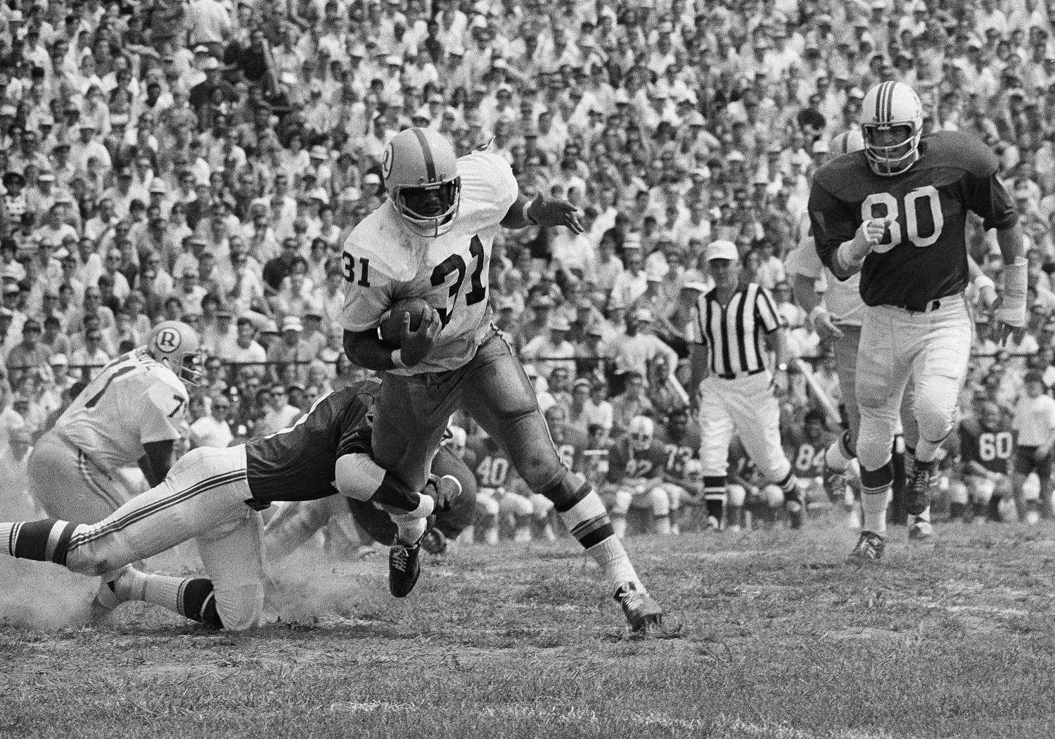 Charley Harraway (31), Washington Redskin back, takes a pass from Sonny Jurgensen and picks up five yards and a first down in the first period of their exhibition game with the Boston Patriots, Aug. 16, 1970, Newton, Mass. Aaron Marsh is the Patriot bringing him down with Spain Musgrove of the Redskins (71) in background. Washington won the game 45-21. (AP Photo)