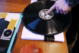During the record-making process, a knife will cut away the excess vinyl from a pressing. Eric Astor, president and founder of Furnace Record Pressing in Fairfax, Va.shows a sample of a record that has not been cut. (WTOP/Tiffany Arnold)
