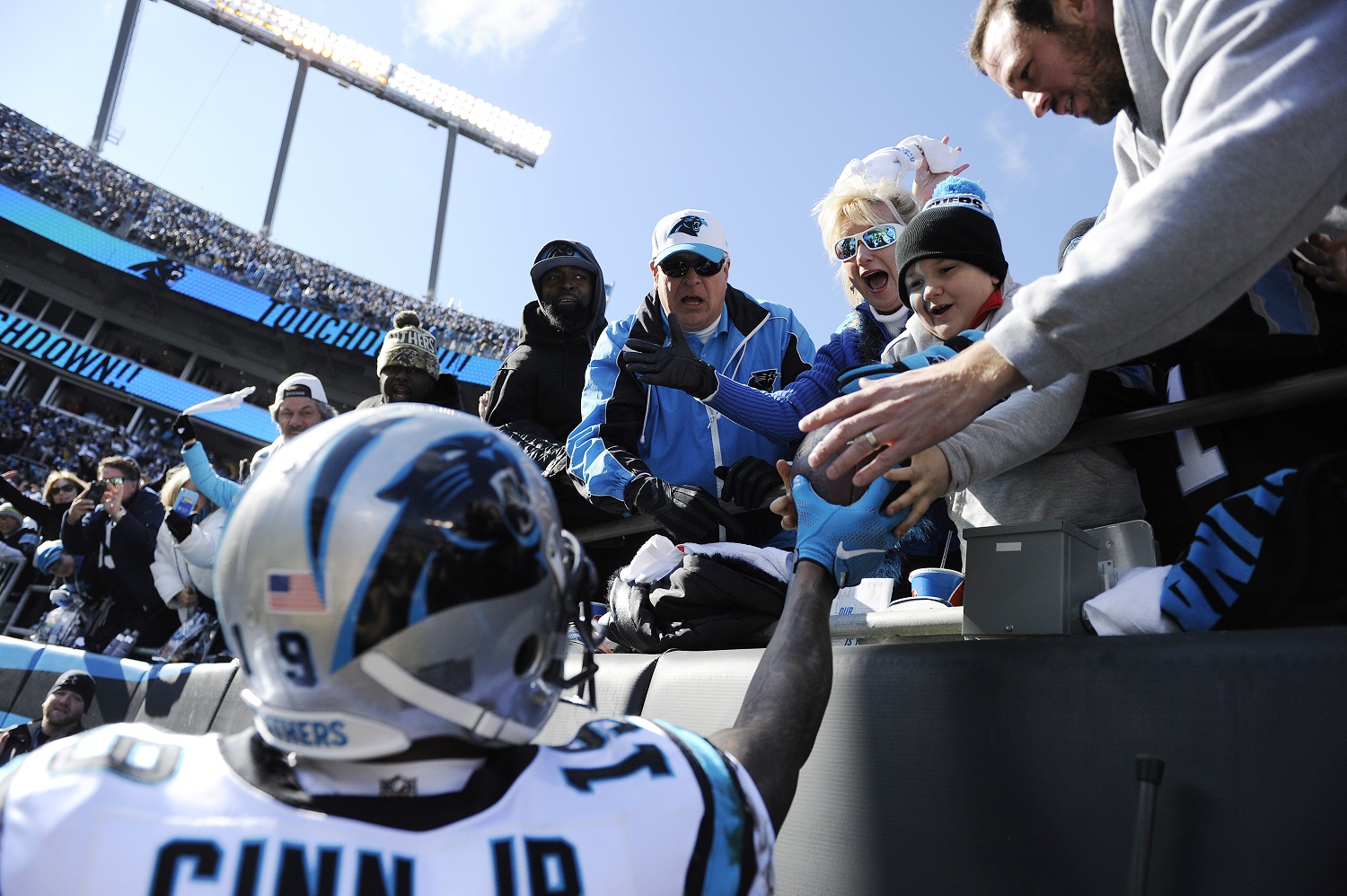 Carolina Panthers wide receiver Ted Ginn (19) hands the ball to a child int he stands after Carolina Panthers tight end Greg Olsen (88) scored a touchdown against the Seattle Seahawks during the first half of an NFL divisional playoff football game, Sunday, Jan. 17, 2016, in Charlotte, N.C. (AP Photo/Mike McCarn)