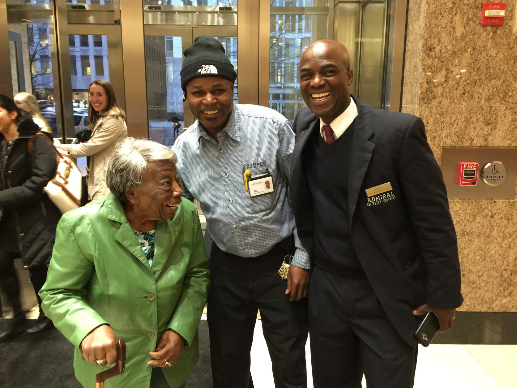 Euton Watson of Bowie, Md. and security officer Kwest Karikari welcome McLaurin to the downtown office building where the 106-year-old White House dancer had yet another interview with media about her experience. (WTOP/Kristi King)