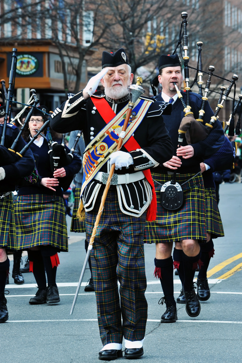 Pipe band member salutes the dignitaries on the review stand. (Photo Shannon Finney/Shannon Finney Photography)
