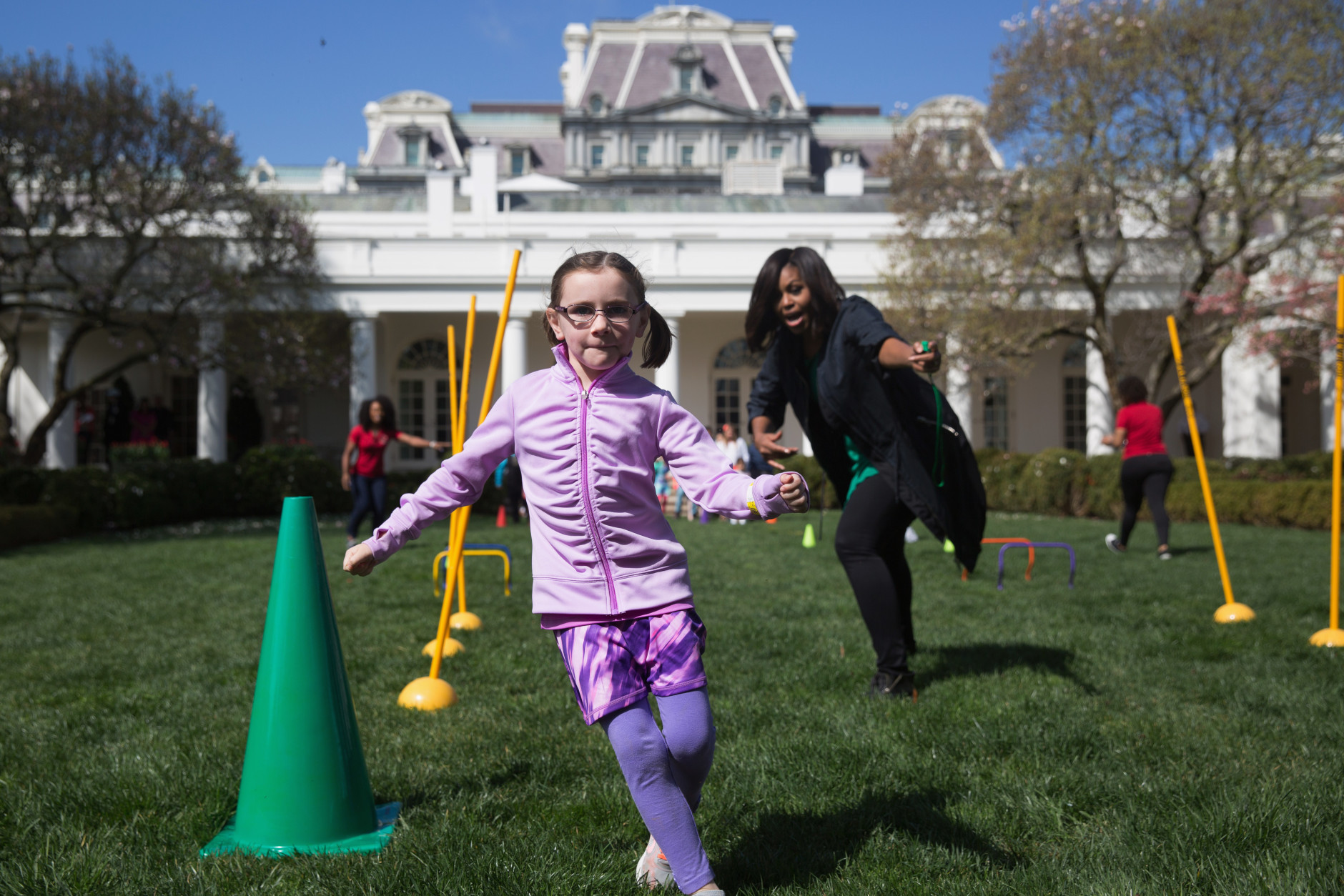 First lady Michelle Obama cheers on children as they run through an obstacle course race in the Rose Garden of the White House in Washington, Monday, March 28, 2016, during the  White House Easter Egg Roll. Thousands of children gathered at the White House for the annual Easter Egg Roll. This year's event features  live music, sports courts, cooking stations, storytelling, and Easter egg rolling. (AP Photo/Andrew Harnik)