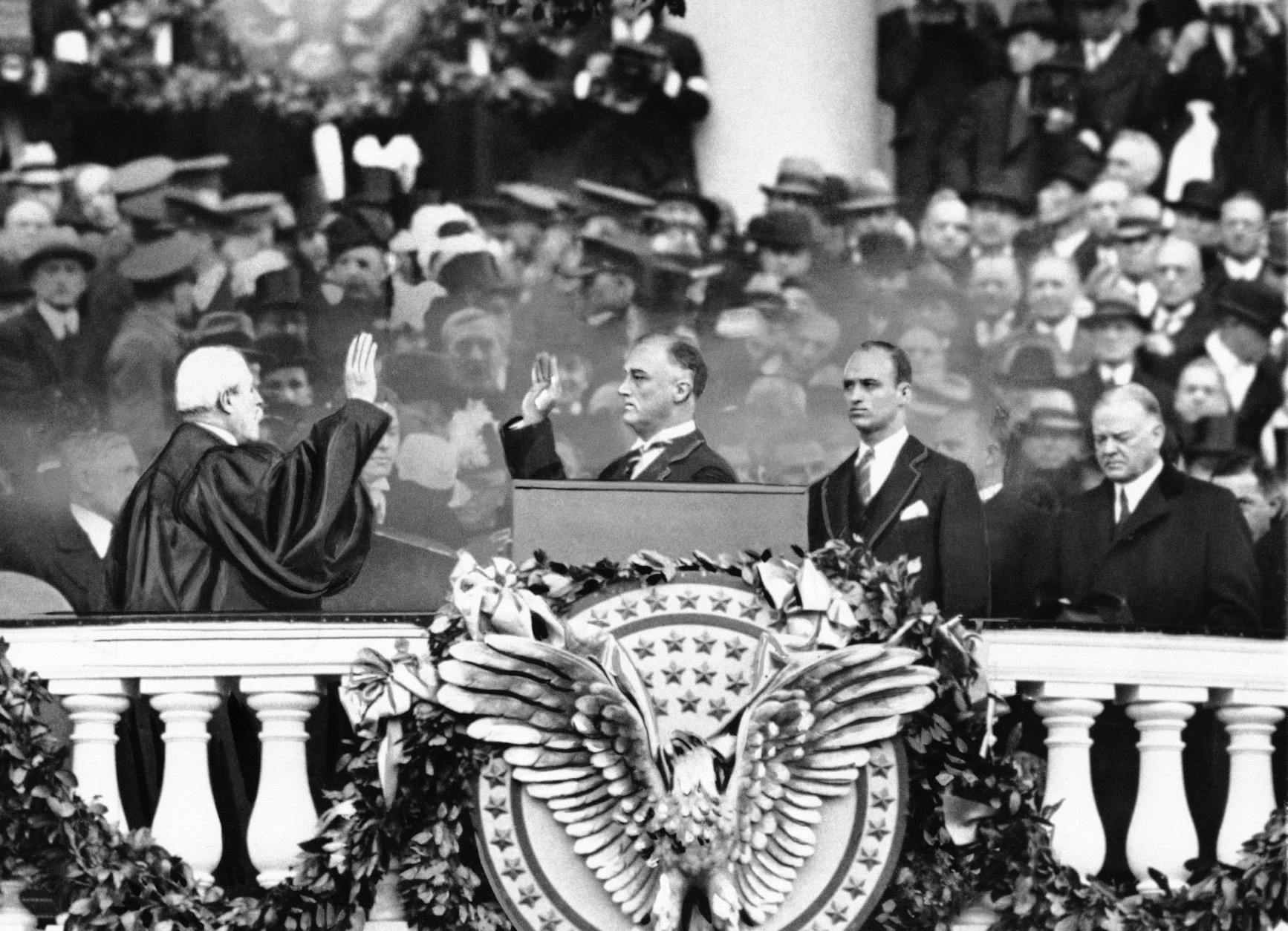 President Franklin D. Roosevelt takes the oath of office from Chief Justice Charles E. Hughes at the inauguration, March 4, 1933. At right is Herbert Hoover and behind the president is his eldest son James Roosevelt. (AP Photo)