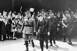 Benito Mussolini, left, and Adolf Hitler move along in step, smilingly accepting the plaudits of Munich residents when they met to discuss armistice terms for beaten France on June 18, 1940. Joyous expressions on faces of women and girls at left as they raise their arms to Heil the axis leaders. (AP Photo)