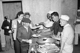 Japanese removed from their Los Angeles homes line up at the governments alien camp at Manzanar, Calif. March 23, 1942 for their first meal after arrival at the camp. Rice, Beans, Prunes bread were included in the menu. (AP Photo)