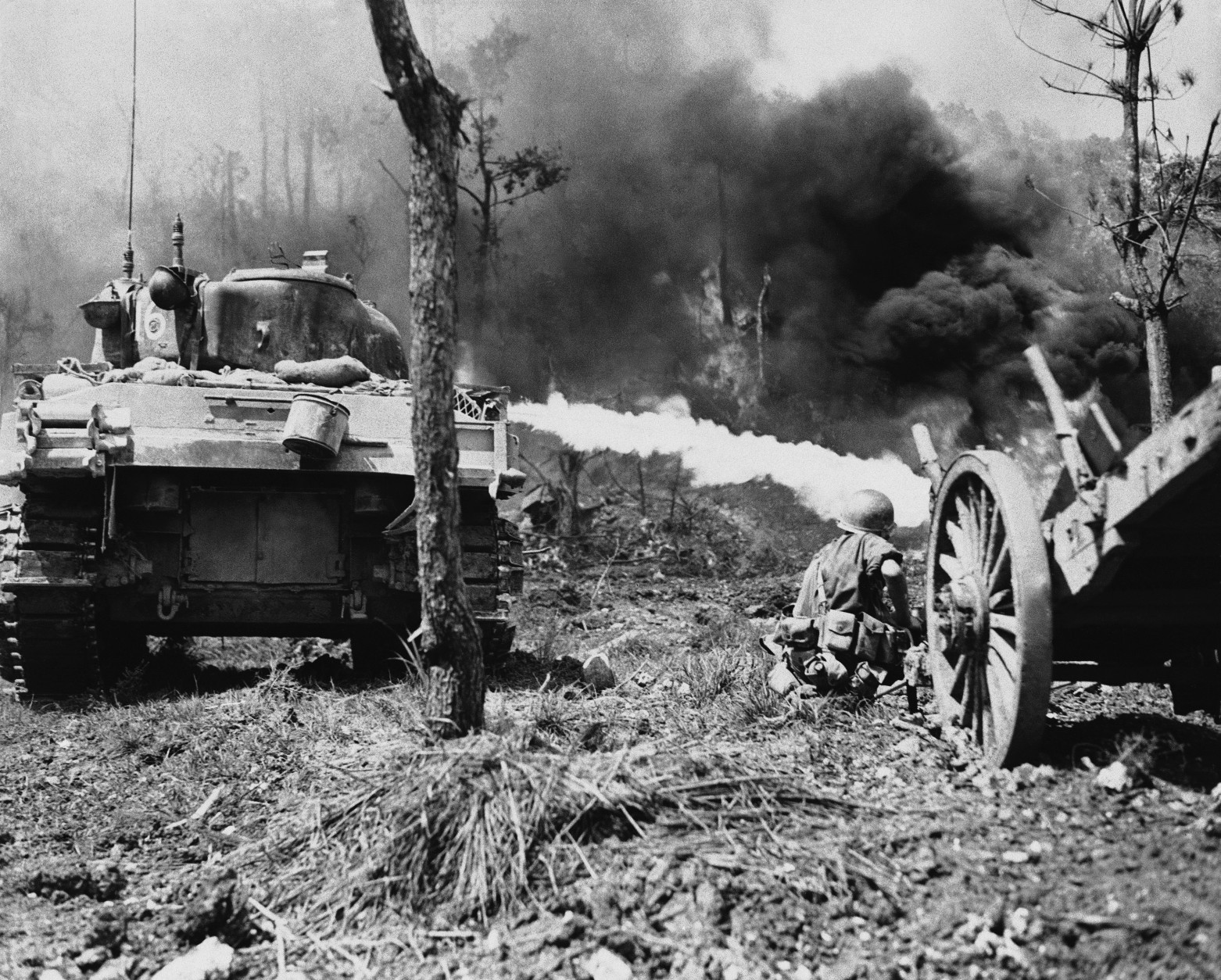 A flame-throwing tank of the U.S. Tenth Army on Okinawa, Japan moves up close to a Japanese position to destroy it with flames during the terrific fighting on the island in the spring of 1945. An infantryman of the 96th Infantry Division crouches, ready to get any of the enemy who might have avoided the flames. (AP Photo)