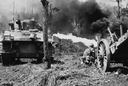 A flame-throwing tank of the U.S. Tenth Army on Okinawa, Japan moves up close to a Japanese position to destroy it with flames during the terrific fighting on the island in the spring of 1945. An infantryman of the 96th Infantry Division crouches, ready to get any of the enemy who might have avoided the flames. (AP Photo)