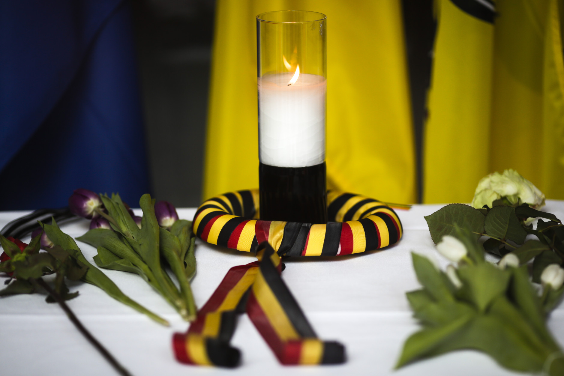After  attacks in Brussels, a candle wrapped in a ribbon in the colors of the Belgium national flag and flowers are  placed on a table inside the Belgium Embassy in Berlin, Germany, Tuesday, March 22, 2016. (AP Photo/Markus Schreiber)