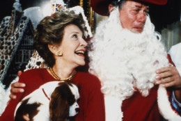 America's First Lady Nancy Reagan holding Rex the dog with Larry Hagman who is dressed as Santa, at the White House, Monday, Dec. 9, 1985, in Washington, USA. Hagman plays J.R. Ewing on the television series "Dallas". The gingerbread house seen behind was created by chef Hans Raffert. (AP Photo/Bob Daugherty)