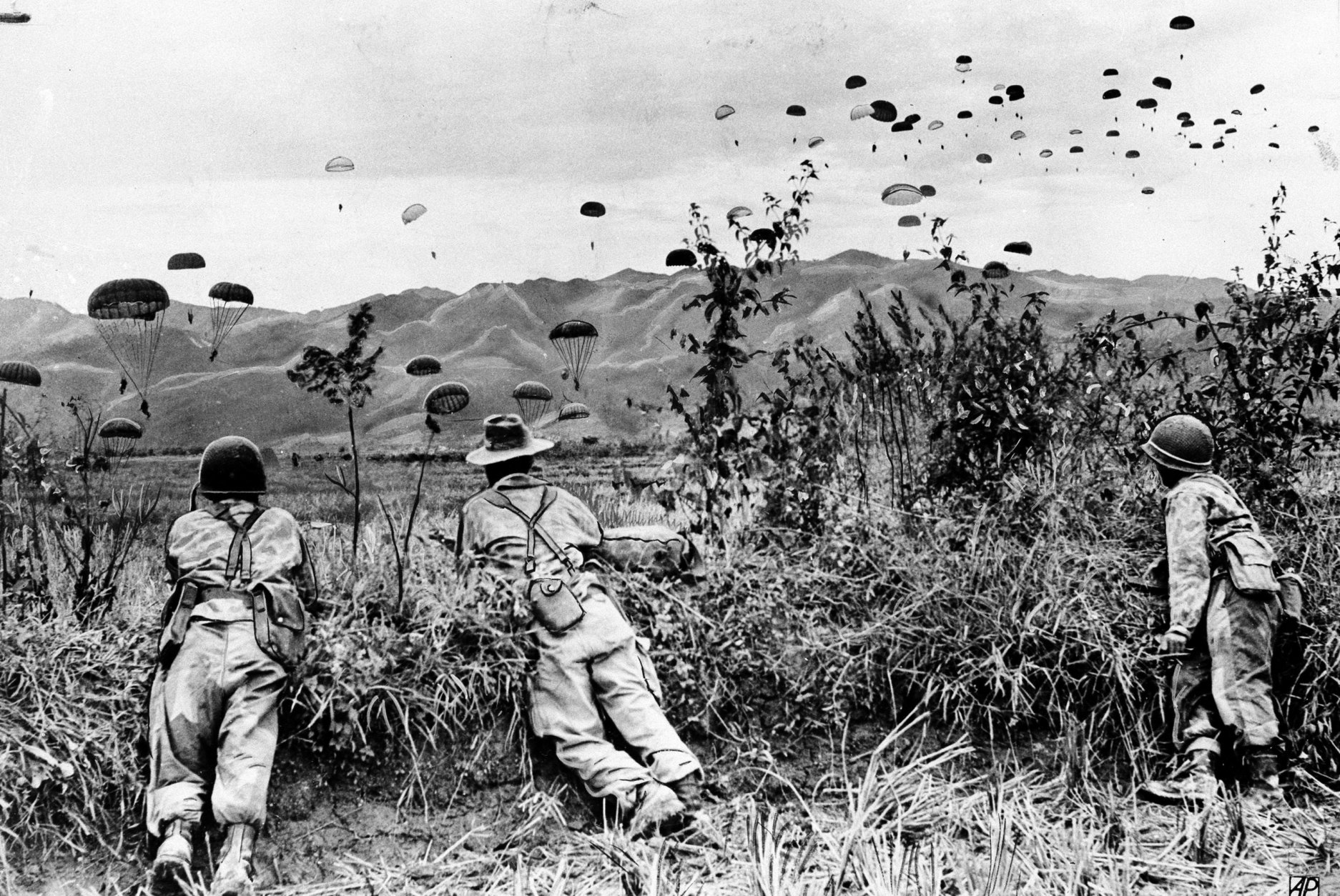 The first landed paratroopers of the French-Indochinese Union army have a watchful eye on the descent of their comrades, as Operation Castor gets under way, on November 20, 1953, in the hill tops district northwest of Hanoi . Several paratrooper units are launched in a campaign to strenghten the garrison of Dien Bien Phu. (AP Photo)