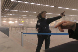 In this photo provided by Ralph Usbeck a police officers directs passengers in a smoke filled terminal at Brussels Airport, in Brussels after explosions Tuesday, March 22, 2016. Authorities locked down the Belgian capital on Tuesday after explosions rocked the Brussels airport and subway system, killing  a number of people and injuring many more. Belgium raised its terror alert to its highest level, diverting arriving planes and trains and ordering people to stay where they were. Airports across Europe tightened security.  (Ralph Usbeck via AP)