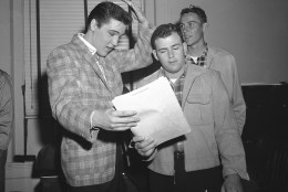 Elvis Presley, left, 23-year-old rock and roll singer, gestures at his short hair as he chats with a former school chum, Farley Gey, 22, who is entering the Army with Elvis, in Memphis, March 24, 1958. Robert Maharrey, 22, another inductee, looks on from the rear. The scene took place at the local draft board headquarters. (AP Photo/Fred J. Griffith)
