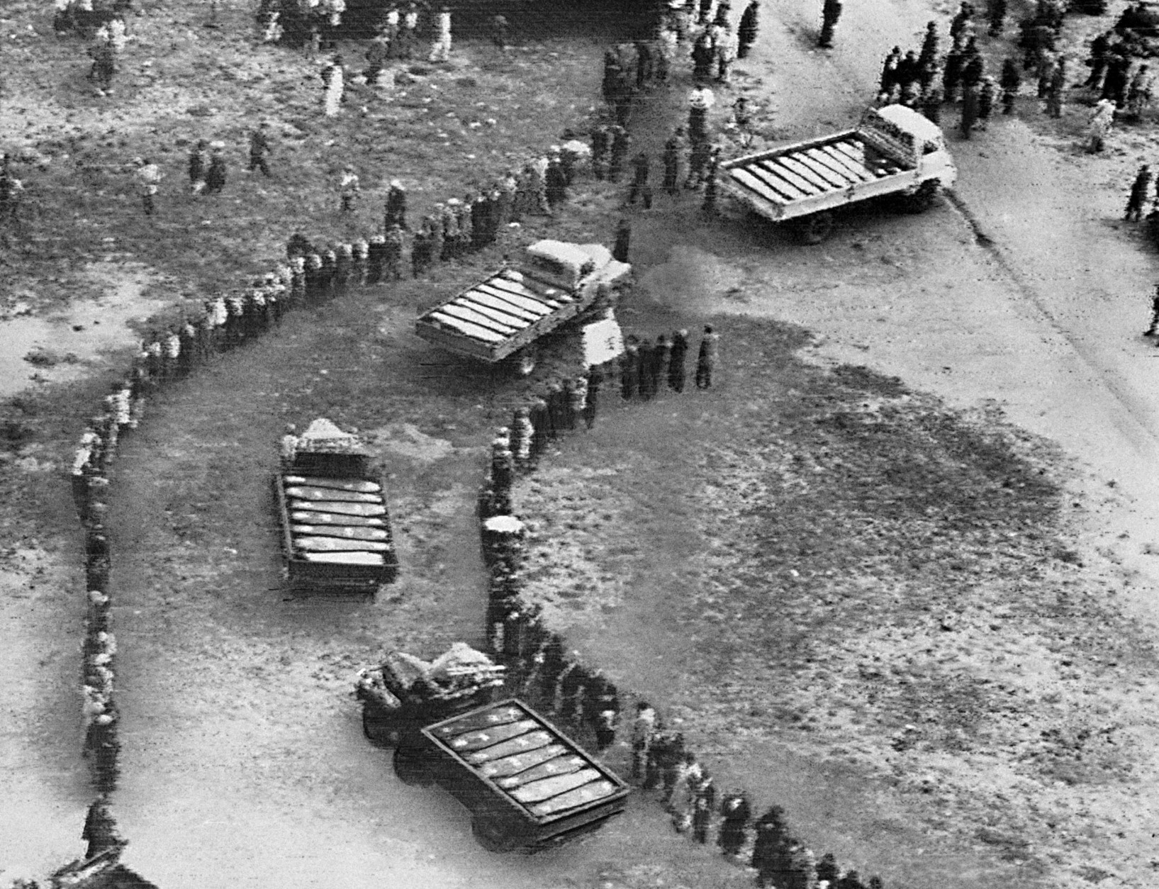 Trucks laden with coffins of black victims of South African shooting roll through lines of mourners during mass funeral ceremony at Sharpeville, south of Johannesburg, South Africa, March 21, 1960. No whites were permitted into the area during the funeral of 34 victims, who were killed by South African white police last week. (AP Photo)