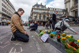 A man looks at flowers and messages outside the stock exchange in Brussels on Tuesday, March 22, 2016. Explosions, at least one likely caused by a suicide bomber, rocked the Brussels airport and subway system Tuesday, prompting a lockdown of the Belgian capital and heightened security across Europe. At least 26 people were reported dead. (AP Photo/Geert Vanden Wijngaert)
