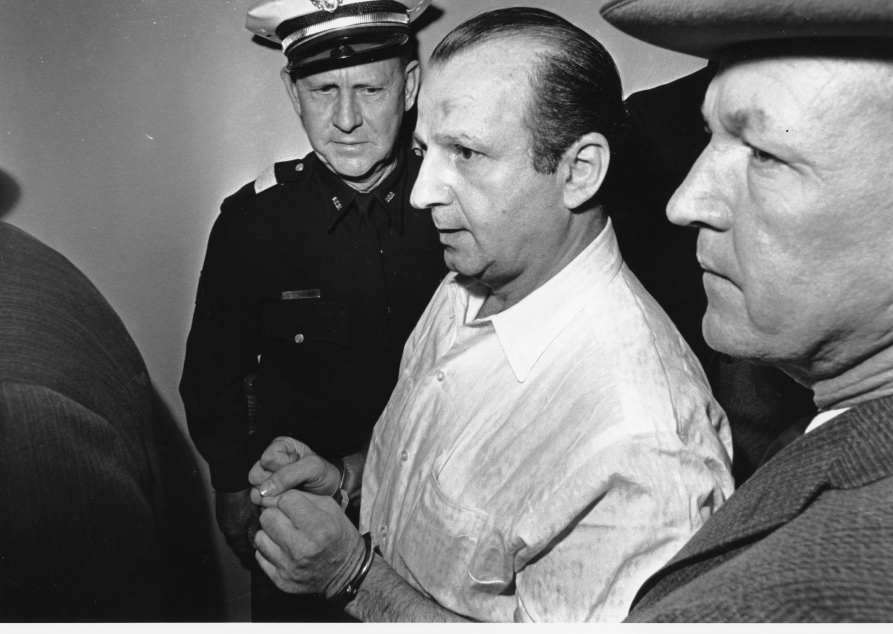 Nightclub owner Jack Ruby is led through the Dallas city jail on his way to his arraignment in Dallas, Tex. on Nov. 24, 1963.  Ruby was charged for the murder of Lee Harvey Oswald, the man accused with assassinating John F. Kennedy.  Others are unidentified.  (AP Photo)