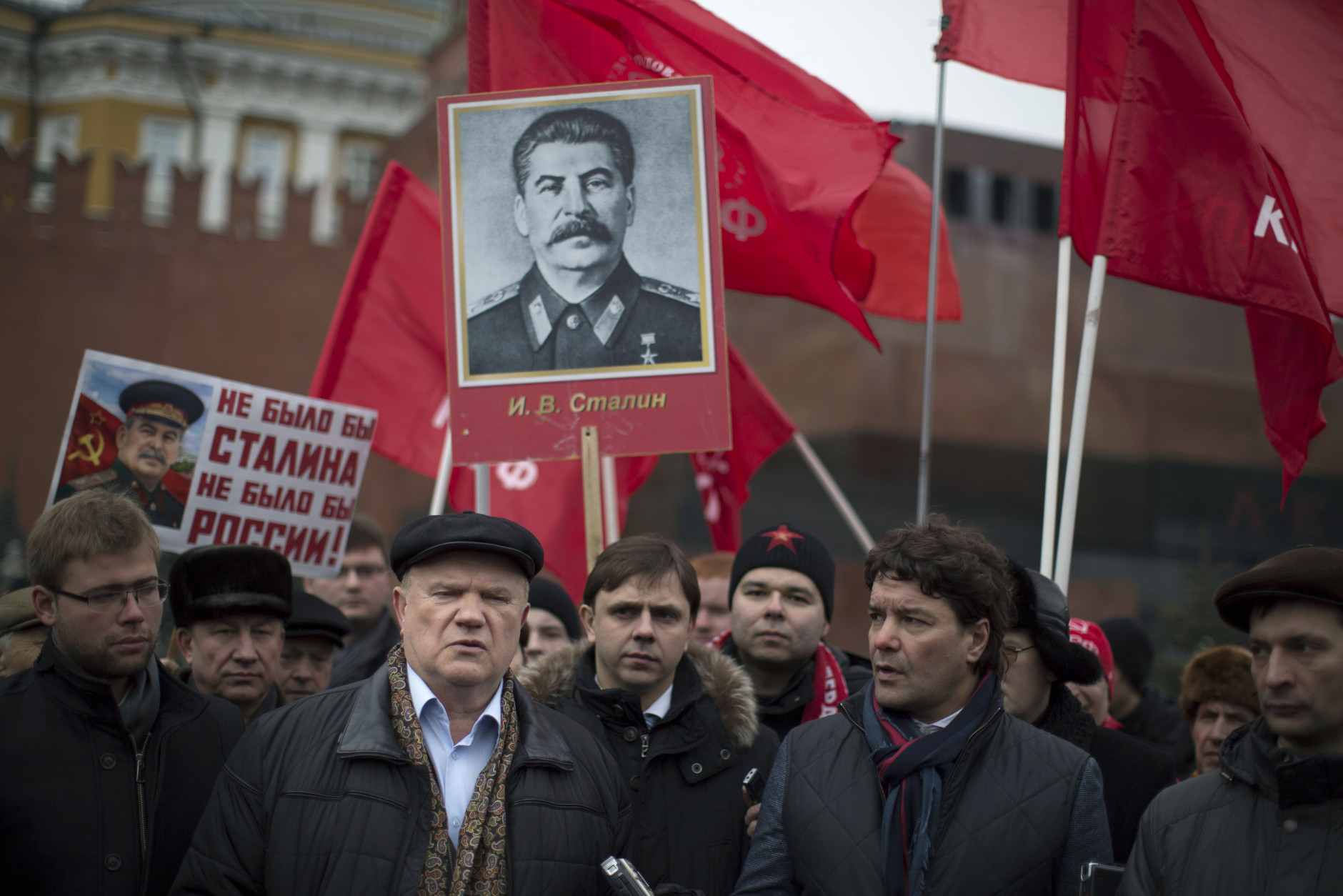 Russian Communist Party leader and lawmaker Gennady Zyuganov, foreground left, speaks to the media as communist party supporters holds portraits of Soviet dictator Josef Stalin and red flags marking the 61st anniversary of his death in Red Square in Moscow, Russia, Wednesday, March 5, 2014.  Stalin led the Soviet Union from 1924 until his death in 1953. Communists credit him with leading the country to victory in World War II while others condemn the brutal purges that killed millions. The sign at left reads "without Stalin there could not be Russia." (AP Photo/Alexander Zemlianichenko)