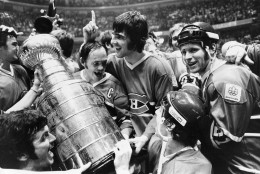 Yvan Cournoyer, captain of the Montreal Canadiens, holds the Stanley Cup as he is surrounded by teammates in Philadelphia, Pa., Sunday night, May 16, 1976.  Montreal beat the Philadelphia Flyers to take the final series of the cup.  (AP Photo)