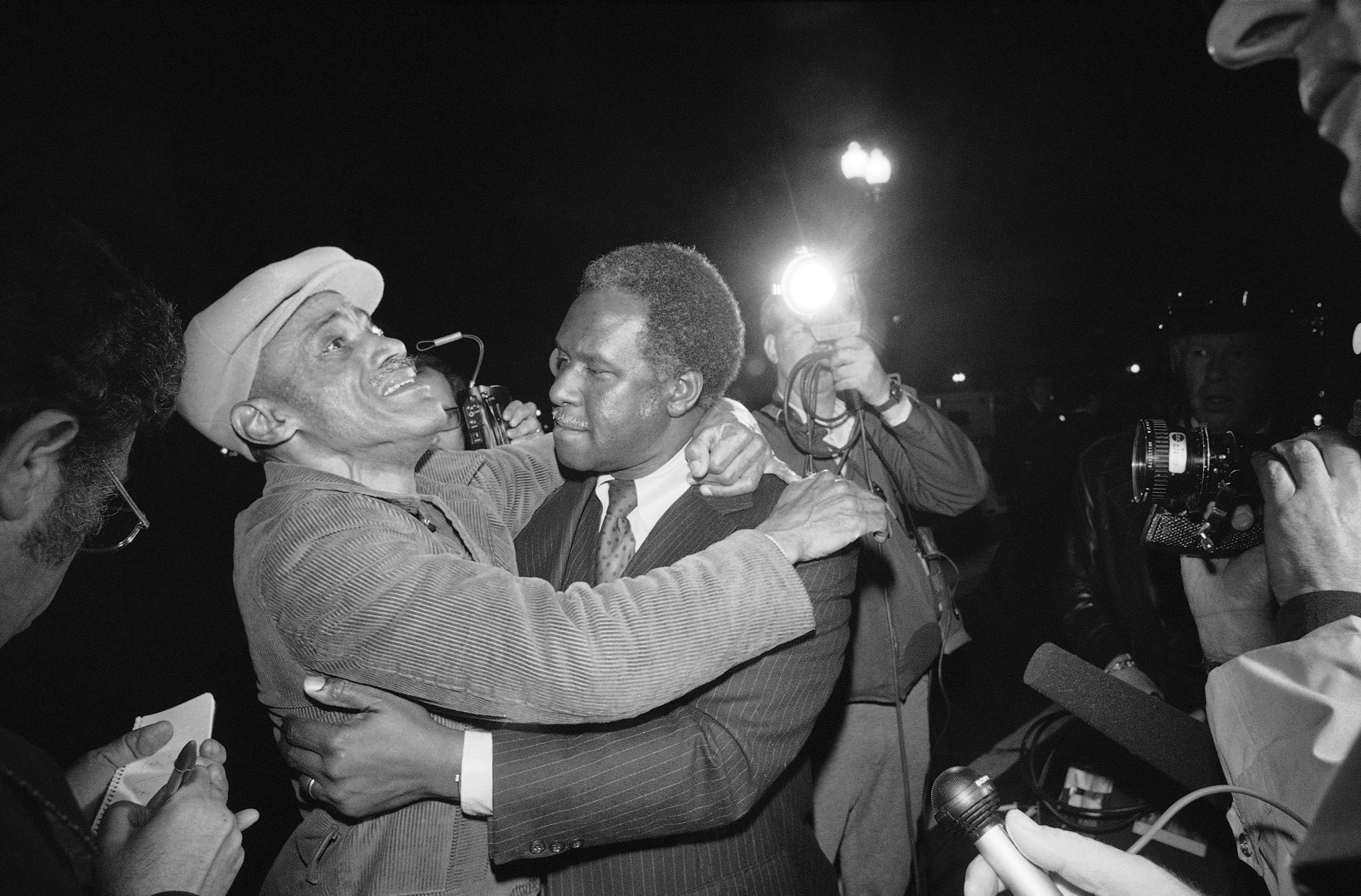 Joseph Yeldell, right, who formerly headed the Districts Department of Human Resources, embraces an unidentified man at the District of Columbia Building in Washington on Friday, March 11, 1977 after the man was released by terrorists who had held a group in the building since Wednesday. (AP Photo)