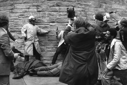 White House press secretary James Brady lies wounded on the sidewalk outside a Washington hotel after being shot during an assassination attempt on U.S. President Ronald Reagan on Monday, March 30, 1981. In the background secret service agents and police wrestle the alleged assailant to the ground. (AP Photo/Ron Edmonds)