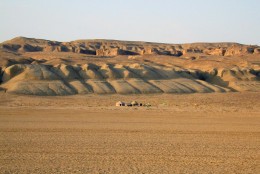 Field camp of the Uzbek-Russian-British-American-Canadian expedition at Dzharakuduk in the Kyzylkum Desert of Uzbekistan. The fossils of Timurlengia eutica were found about midway along the cliffs in the background. (Courtesy Proceedings of the National Academy of Sciences)