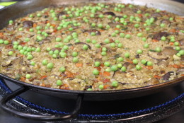 At the very end, Meltzer spreads fresh English peas over the top of the paella. (WTOP/Dana Gooley)