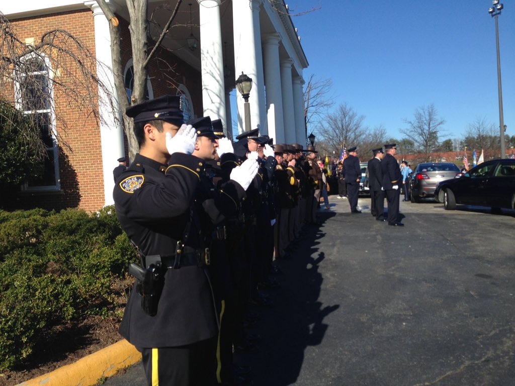 As bagpipes play, officers salute Officer Ashley Guindon. (WTOP/Jamie Forzato)