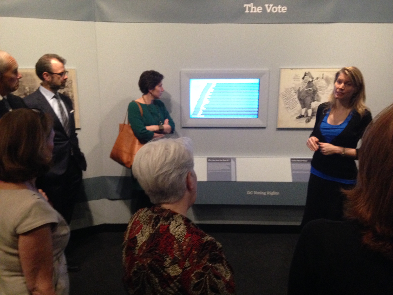 Co-curator Christine Blackerby explains the right to vote section of the exhibit to visitors. (WTOP/Megan Cloherty)