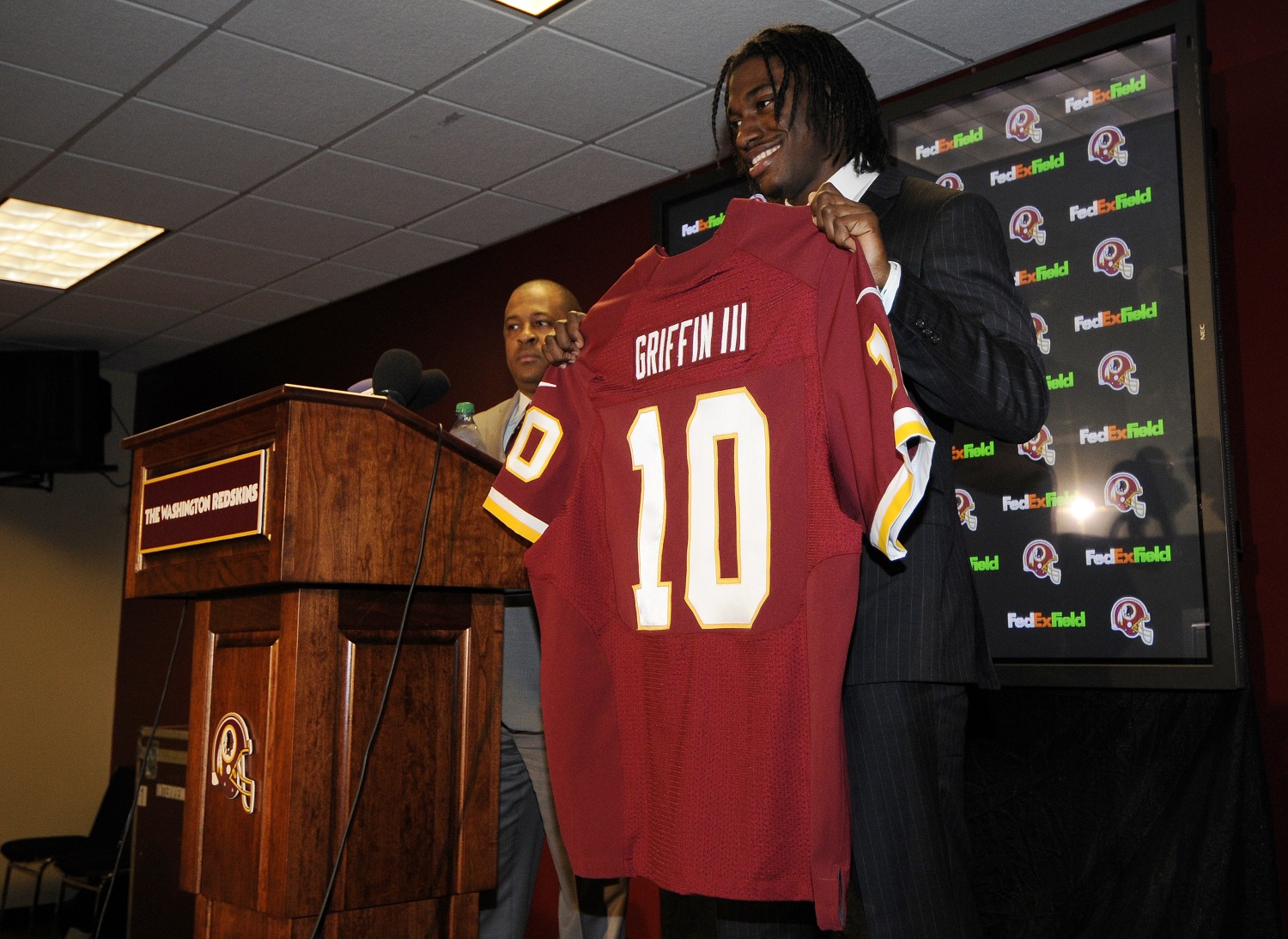 Washington Redskins first round NFL football draft pick, Robert Griffin III, poses with a Redskins jersey at a press conference, Saturday, April 28, 2012, in Landover, Md. (AP Photo/Nick Wass)