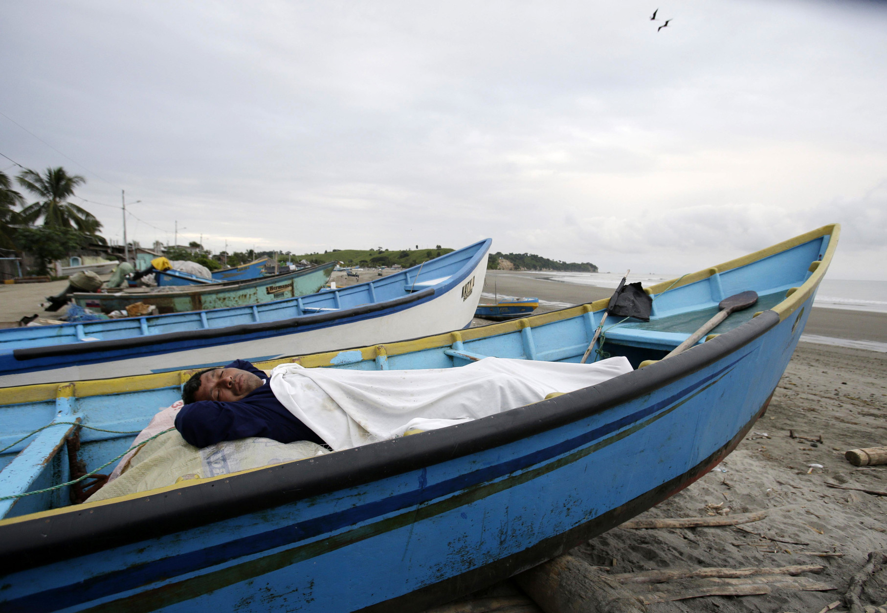 A man, his home destroyed by a 7.8 magnitude earthquake, sleeps in his uncle's boat docked along the shore, in La Chorrera, Ecuador, Monday, April 18, 2016. The Saturday night quake left a trail of ruin along Ecuadors normally placid Pacific Ocean coast. At least 350 people died and thousands are homeless. President Rafael Correa said early Monday that the death toll would surely rise, and in a considerable way. (AP Photo/Dolores Ochoa)