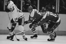 New York Islanders center Bryan Trottier, left, directs the puck against pursuing Washington Capitals in Uniondale, New York, April 7, 1983. Hot on Trottier's heels are Caps Milan Novy, center, and Bob Carpenter in the third period at Nassau Coliseum. Isles beat the Caps 5-2 with Trottier scoring two for the Isles. (AP Photo/Richard Drew)
