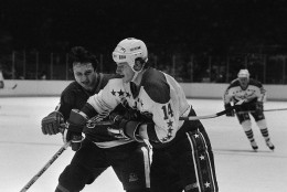 Brad Park of the Detroit Red Wings, left, tries to keep Gaetan Duchesne of the Washington Capitals from getting to a loose puck along the boards by holding him back with his stick. Action took place in the second period of their NHL game at the Capital Center in Landover, Maryland Dec. 9, 1984. (AP Photo/Joe Giza)