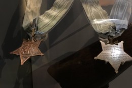 Medals of Honor rest inside a glass case. The pendant have been flipped to reveal the names of those they honored. (WTOP/ Kristi King)